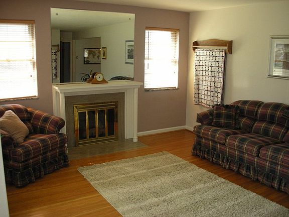Open living room with gas log fireplace. Gleaming hardwood floors