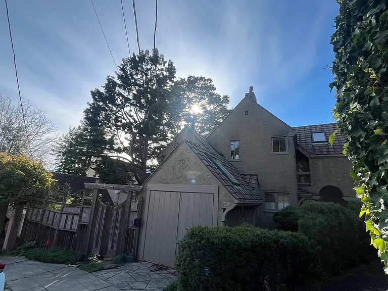 House nested in wooded area with tree and fence.