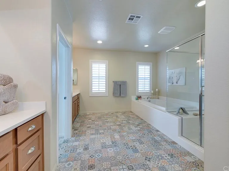 Maser Bathroom with dual vanity, bathtub, and shower