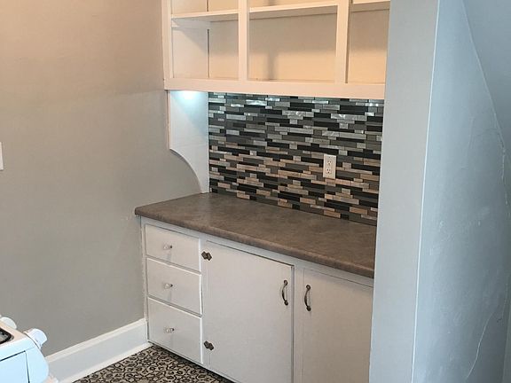 open cabinets with lower storage and glass backsplash