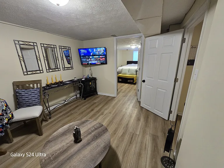 Clean and updated common area with TV, modern flooring, and easy access to bedroom and bathroom