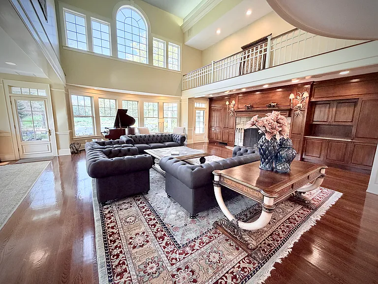 View of the richly decorated great room with seating for up to seventeen, a massive stone fireplace, and a grand piano.