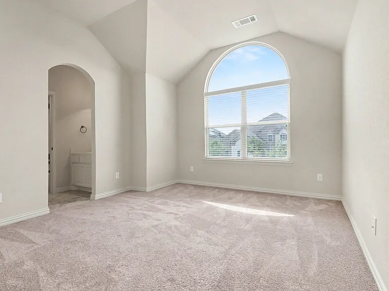 Room featuring vaulted ceilings and an arched window with horizontal blinds