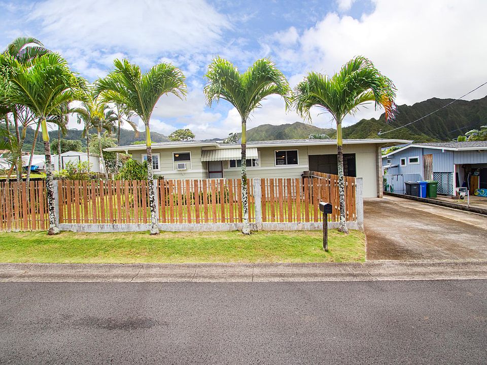 The front of the home is lined with palms. The one-car carport and driveway provide plenty of room to park your cars..