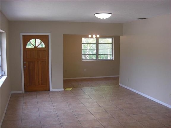 Looking across den / living room towards front door and dining area (to right). Kitchen behind wall on right.