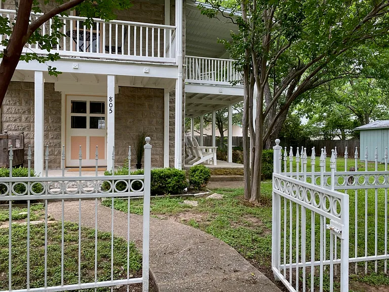 White fence along the front with three gates. Two porches down, two balconies up.