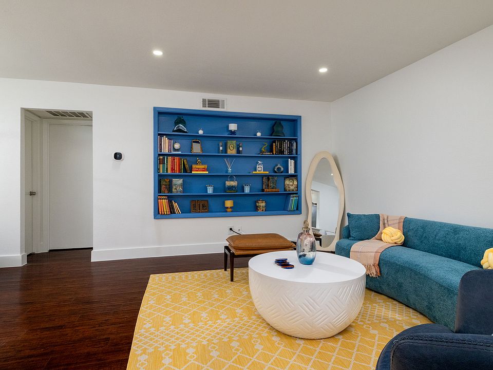 Relax in a bright and stylish living room featuring cozy blue seating, warm accents, and a modern round coffee table. Perfect for lounging, reading, or gathering with friends.