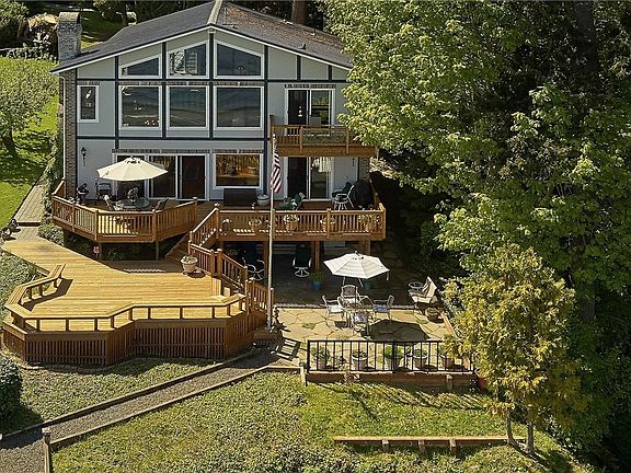 The water side of the home shows the incredible series of entertaining decks and patio which lead down to the private 118 feet of fully bulk headed water frontage.