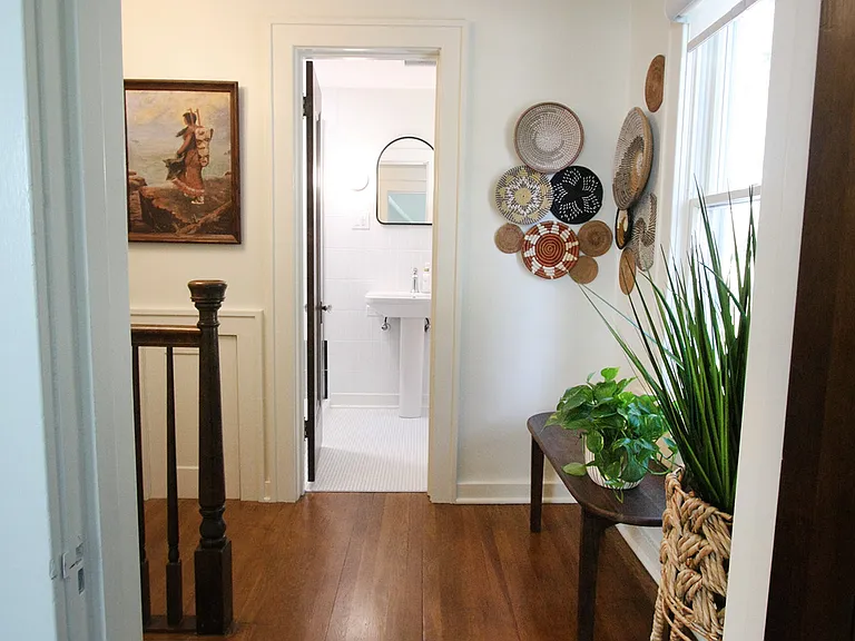 Staircase leads to two upper bedrooms and full bathroom. Hallway closet is filled with extra towels and supplies.