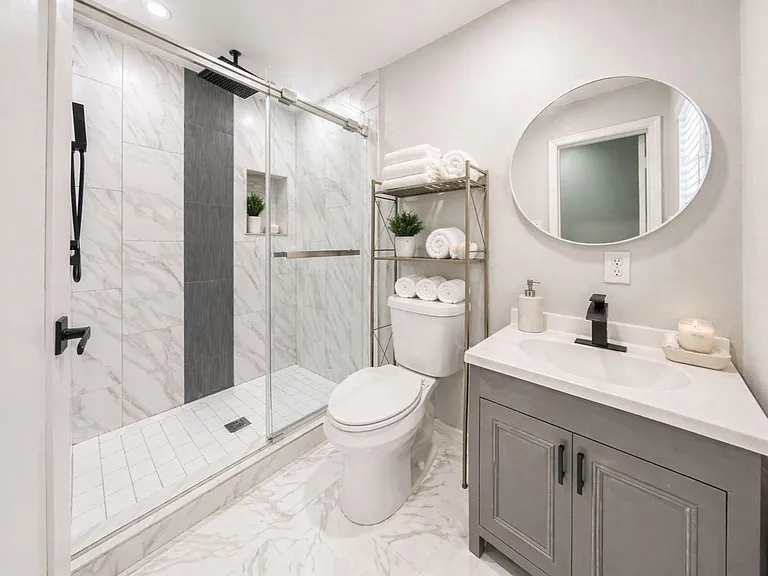 Updated bathroom with a tiled walk-in shower, single-sink vanity, and convenient open shelving for linens and essentials.