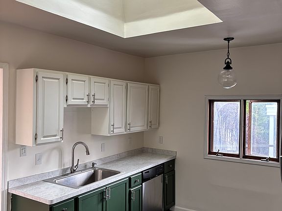 Kitchen with dishwasher, vaulted ceiling, and skylight