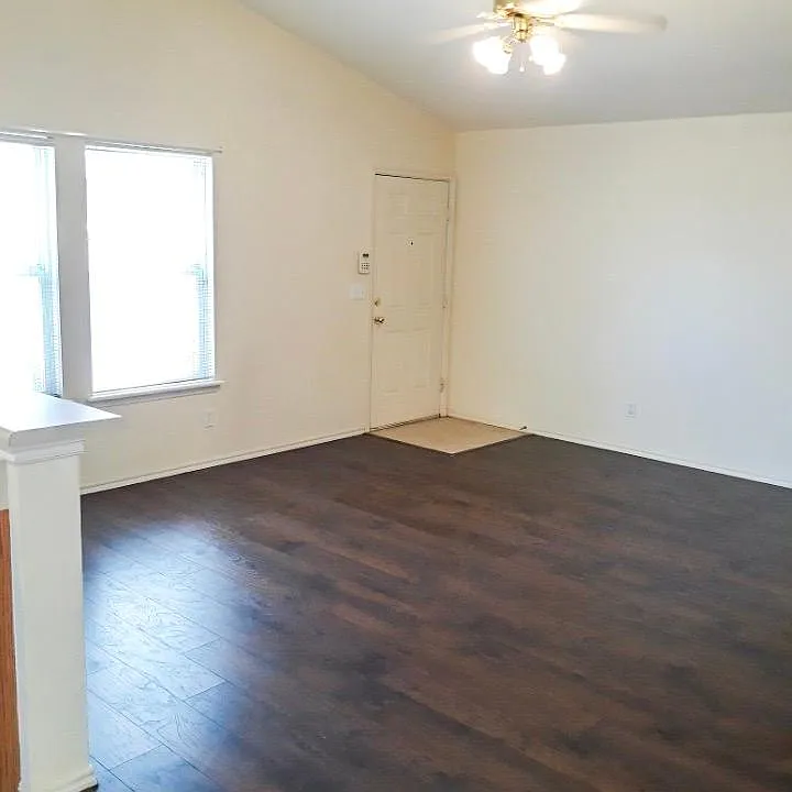 High vaulted ceiling, laminate flooring, and large living room windows for plenty of light.