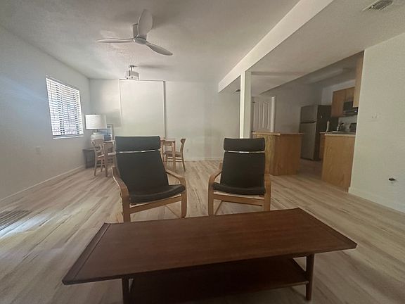 Living room with table and 6 chairs, coffee table, 2 ikea poang chairs and leather coach. Kitchen island.