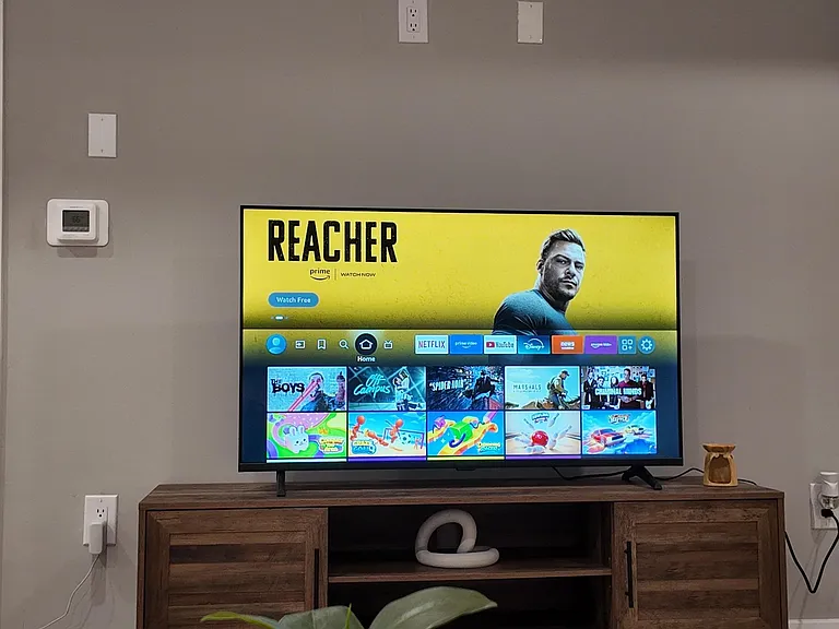 Common lounge area with a wall-mounted TV, media console storage, and space for seating around a coffee table.