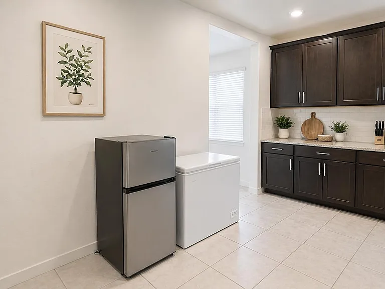 Kitchen features dark cabinetry, generous counter space, tile flooring, and convenient extra cold storage with a mini fridge
