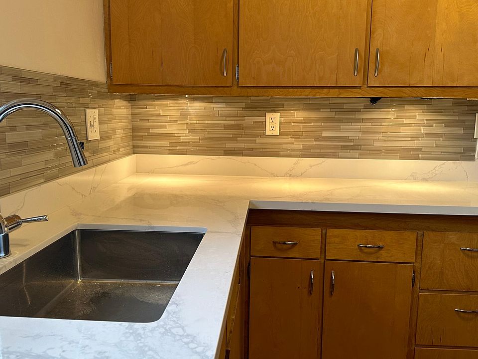 Kitchen with new Quartz countertops, pull down faucet, glass tile backsplash and under cabinet lighting.