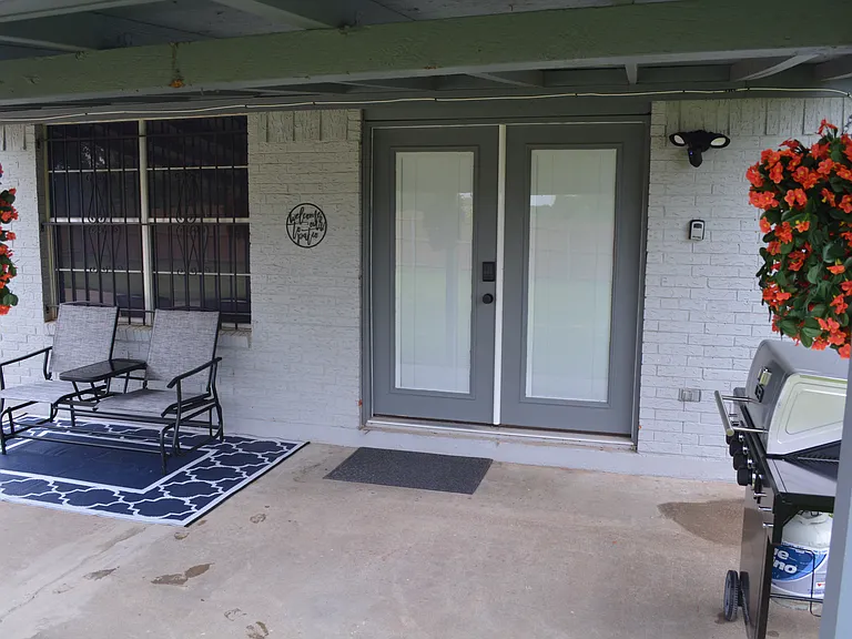 Covered patio area with outdoor furniture and a BBQ grill.