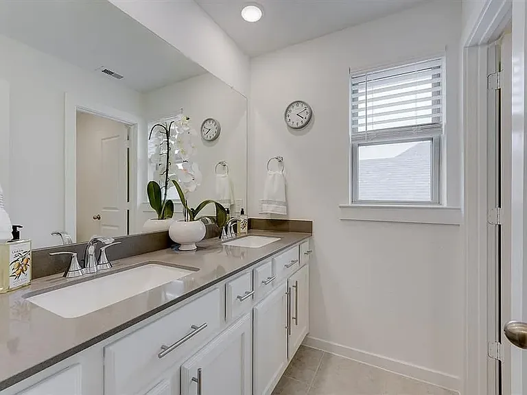 The upstairs bathroom with dual sinks and a large vanity mirror