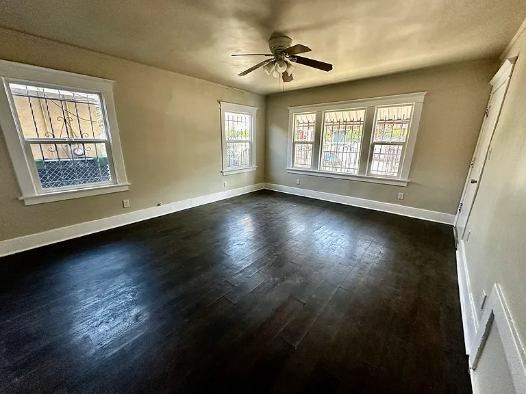 Huge living room with lots of natural lights, windows, and ceiling fan.
