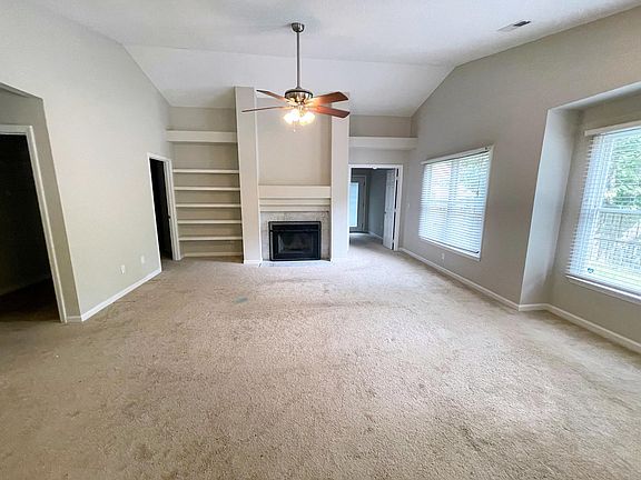 Living room with marble-tiled fireplace and open, built-in shelves