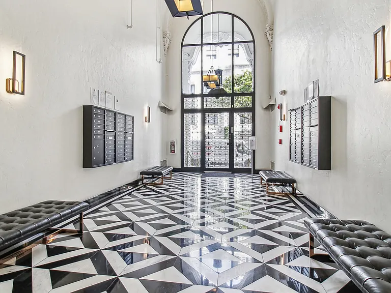 Lobby with a high, arched doorway and large glass panels allow natural light to brighten the space, wall-mounted mailboxes
