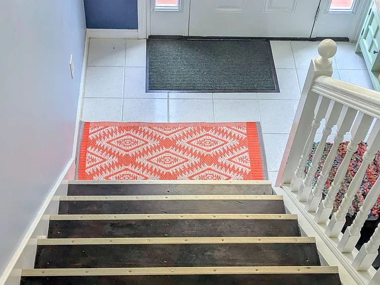Welcoming entryway with tiled landing, staircase with handrail, and a front door with sidelights for added natural light.