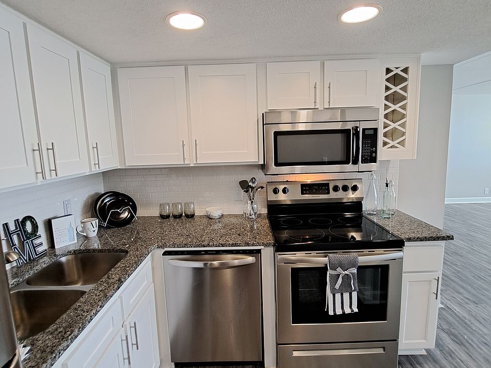 Kitchen equipped with Stainless steal refrigerator, electric stove, microwave, granite countertops, white subway tile and white shaker cabinets.