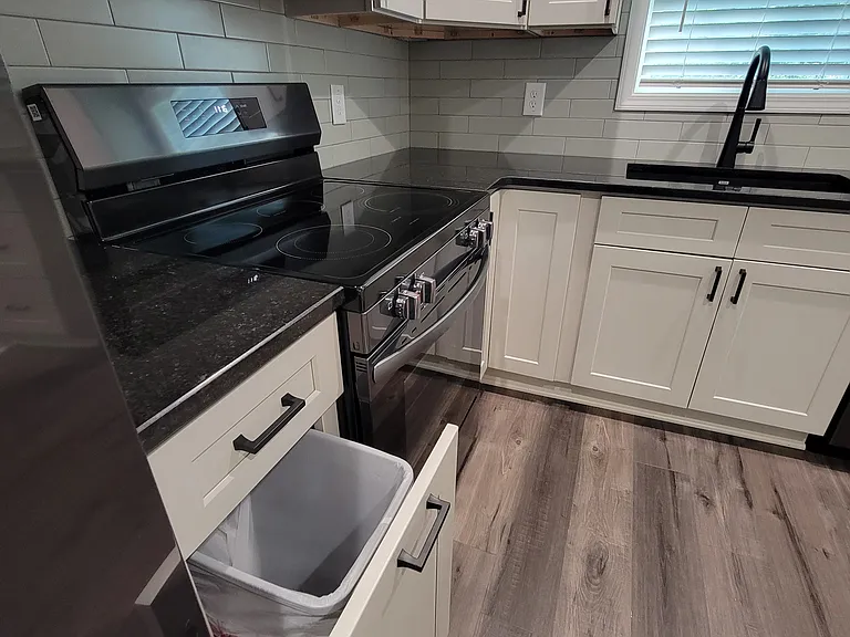 Hide-away trash can designed in custom cabinets.
