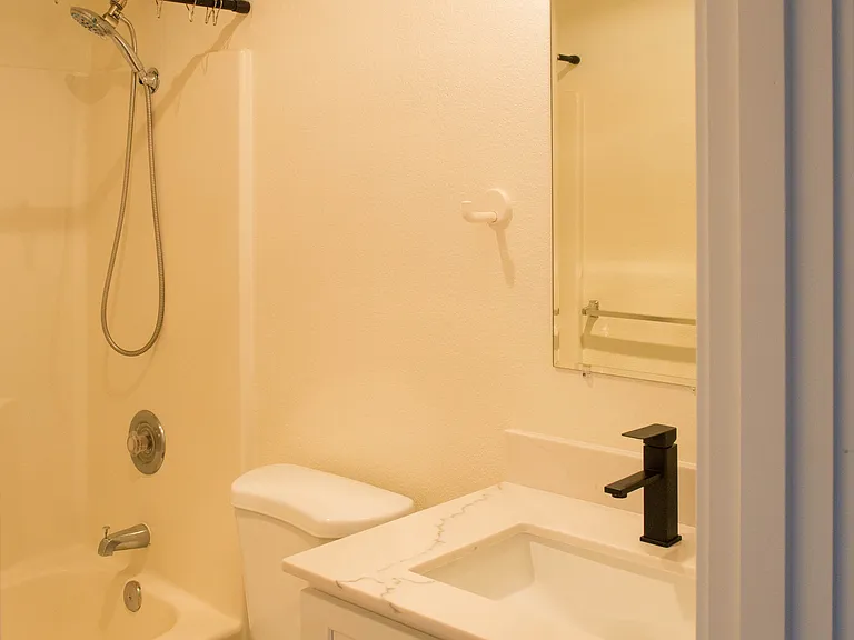 Updated full bathroom with modern vanity, black fixtures, and clean contemporary finishes. Bright, refreshed space with shower and bathtub combination.