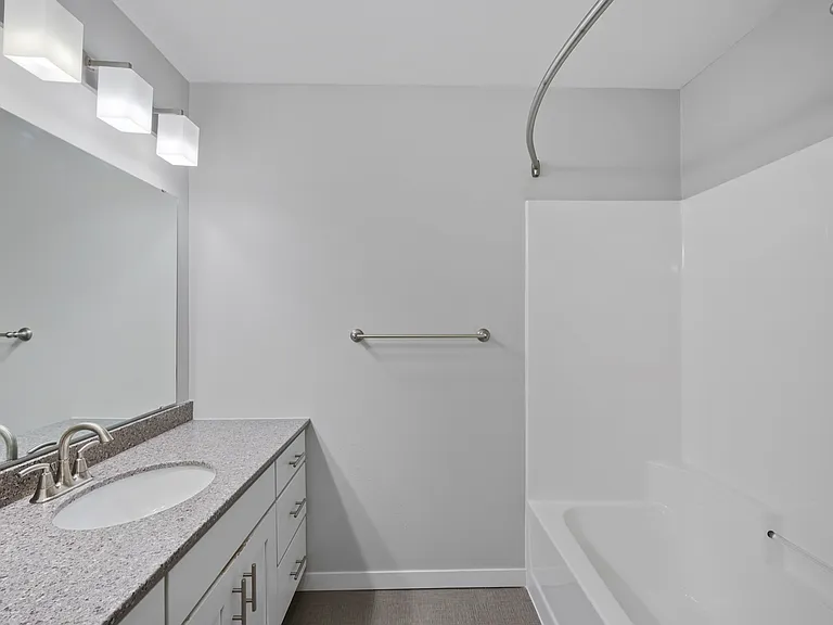 Modern bathroom with sleek fixtures, elegant vanity with granite countertop, and a spacious bathtub area. Modern bathroom with sleek fixtures, elegant vanity with granite countertop, and a spacious bathtub area.