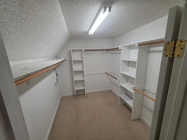 Walk-in closet with wall-mounted organization racks inside Primary Bathroom
