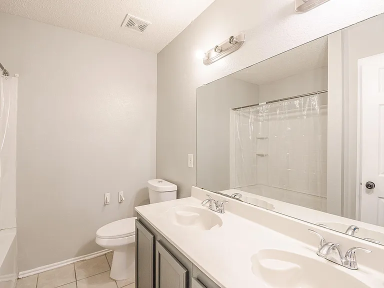 Full bathroom with a double-sink vanity, large wall mirror, and a shower/tub combo for easy daily routines.