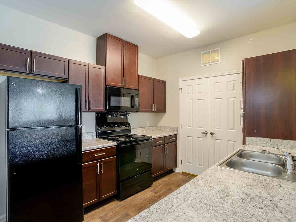 Stylish kitchen featuring black appliances, granite-style countertops, dark wood cabinetry, and pantry space at Cedar Terrace Apartments.