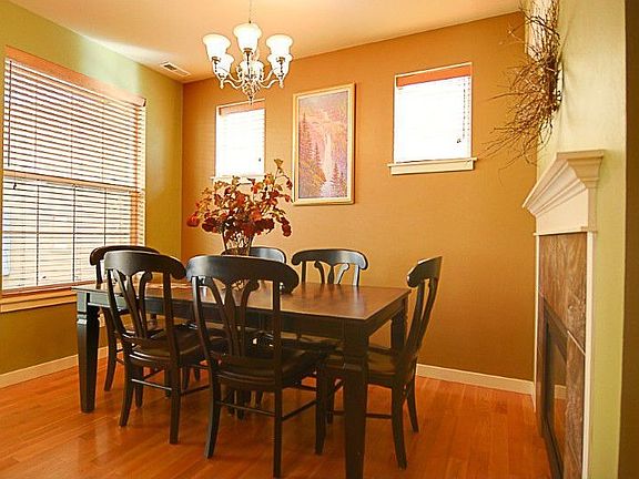 Dining Room features wide-planked hardwood floors, double-sided gas fireplace, and door (to the left of photo) leading to back patio.