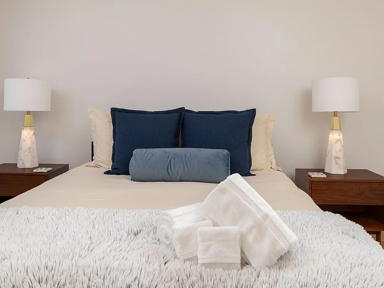 Primary bedroom showcases new artwork, a queen bed, floor-to-ceiling windows for natural light, and an attached bathroom for added convenience.