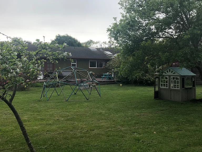 The play structures in this image will be gone when new tenant moves in. On the left is a small fuji apple tree. The back yard is about .5 of an acre and ideal for a gardener.