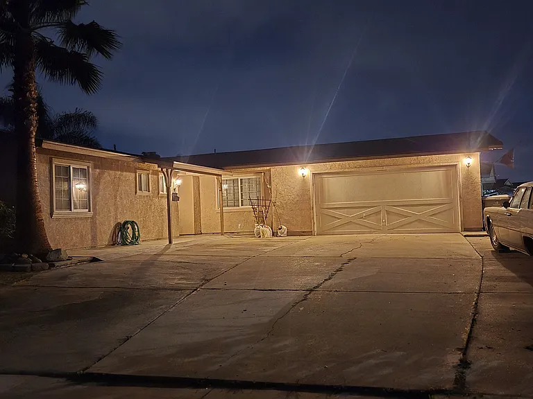 Nighttime view of the front with ample driveway parking