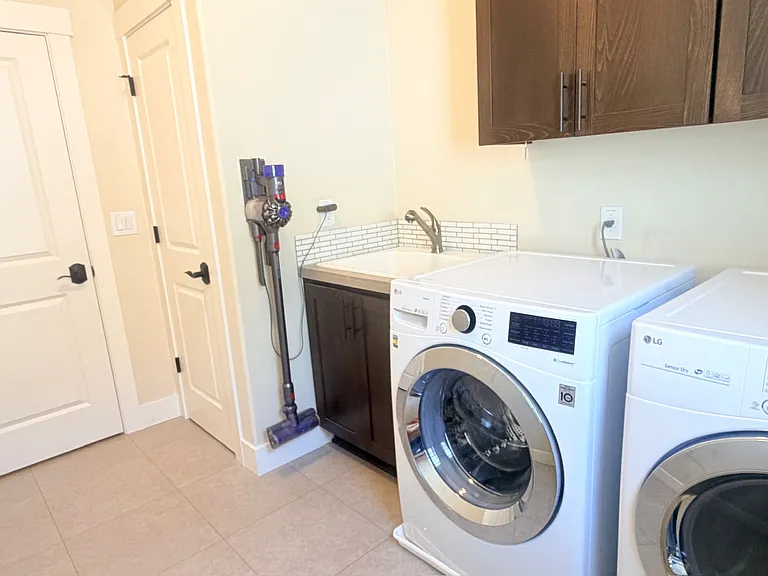 Laundry room with washer, dryer, sink, and cabinets.