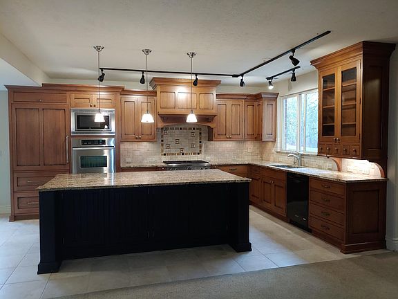 Kitchen and back of island. Subzero refrigerator w/ cabinet door front. Kitchenaid double oven and microwave. 36" Kitchenaid cooktop w/ 4 gas burners and built-in griddle. Kitchenaid warming drawer and dishwasher. Spice pull-outs and other accessories.