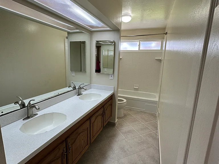 Hall bath with shower over tub and dual vanity.