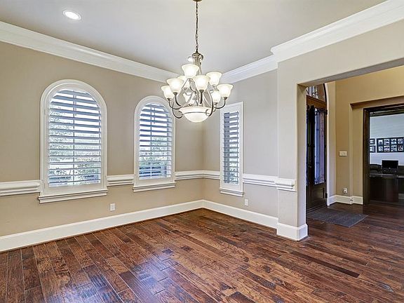 The formal dining room has custom plantation shutters and timeless crown molding.