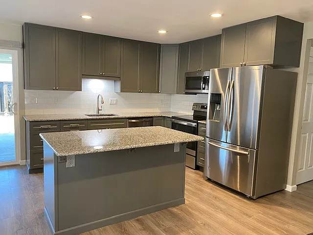 Remodeled kitchen with stainless steel appliances, granite countertops, tile backsplash and island.