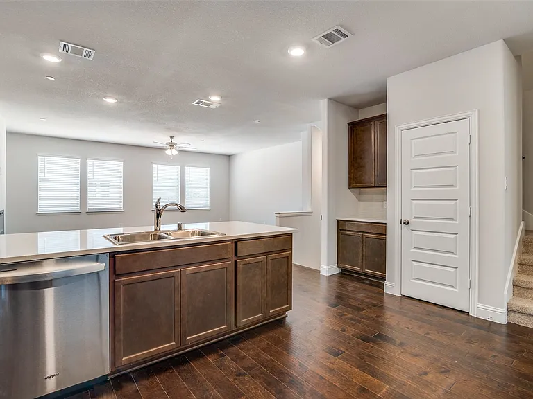 Kitchen island featuring a double-basin stainless steel sink, integrated dishwasher, and light-toned countertop