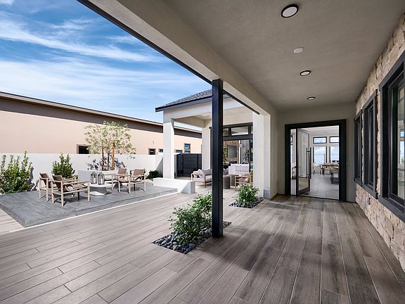 A modern and spacious indoor-outdoor living space with a wooden deck, potted plants, and a view of t