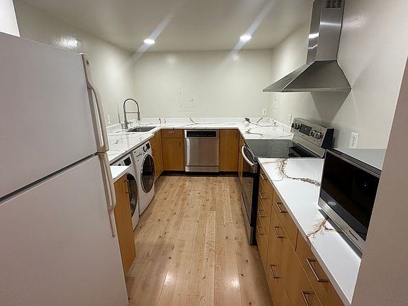 Step into the newly renovated kitchen featuring sleek quartz countertops, a brand-new sink, faucet, and garbage disposal. The space is equipped with almost-new appliances_including a washer, dryer, stove, and microwave.