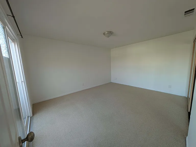 Looking into your large bedroom from the hallway door. Closet is to the right and the sliding glass door leading to the balcony is to the left.