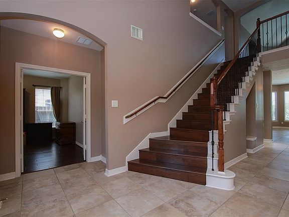 Large tiled entry with wood stairs and wrought iron spindles.  Very open and bright.