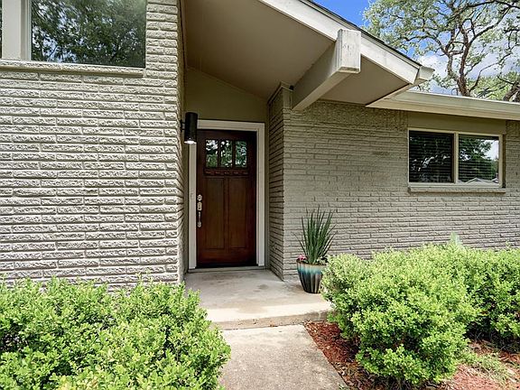 Landscaped front flower beds with beautiful wood and glass front door.