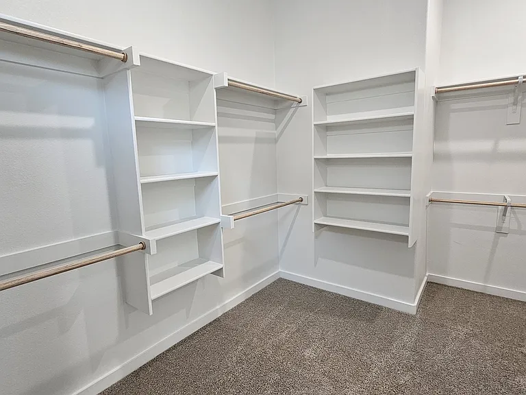 Massive walk-in primary closet with extensive built-in shelving and ample hanging space