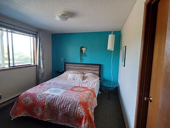 Single bedroom with queen bed connects to full bathroom with W/D in unit.